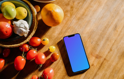 iPhone 13 Pro mockup on a table next to a bowl of fruits