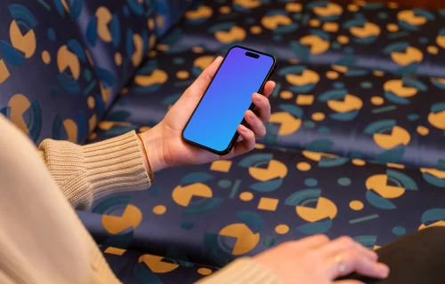 iPhone mockup held by woman’s hand in the lounge