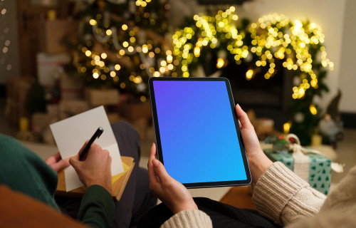 Woman holding a tablet mockup with Christmas decor