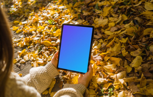 Woman holding an iPad Air in the leaves mockup