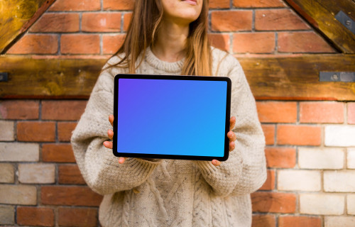 Woman holding an iPad in front of brickwall mockup