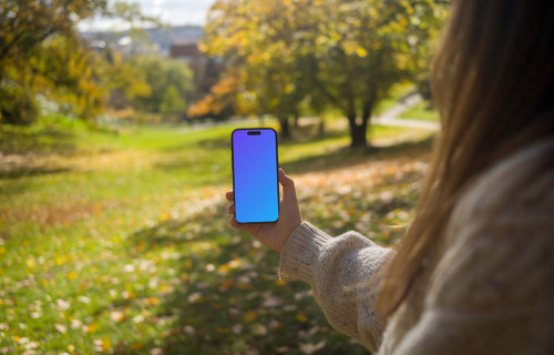 Woman holding an iPhone 14 Pro in nature mockup