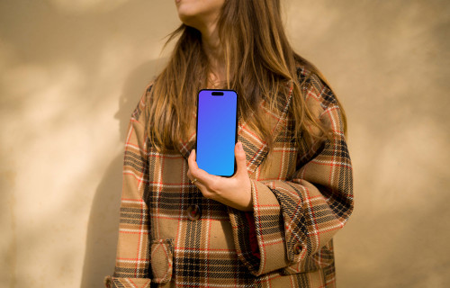 Woman in coat holding an iPhone 14 Pro mockup