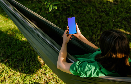 Woman laying in hammock holding a phone mockup