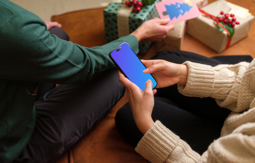 Woman surrounded by Christmas gifts typing on a phone mockup