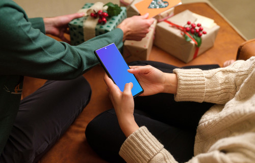 Woman typing on a phone mockup next to the Christmas gifts