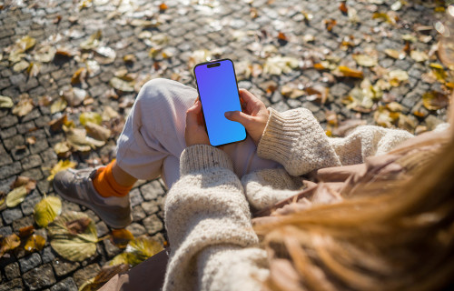 Woman typing on an iPhone 14 Pro in autumn park mockup