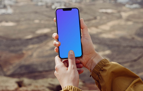 iPhone 13 Pro mockup held with both hands by a user outdoors