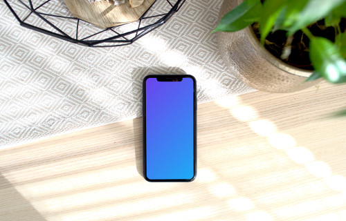 iPhone mockup on a table with a flower pot at the side.