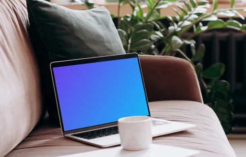 MacBook Pro mockup on a sofa with coffee and documents