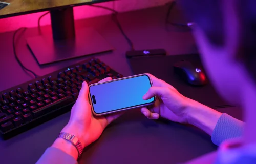 Male hands holding an iPhone mockup in gaming room