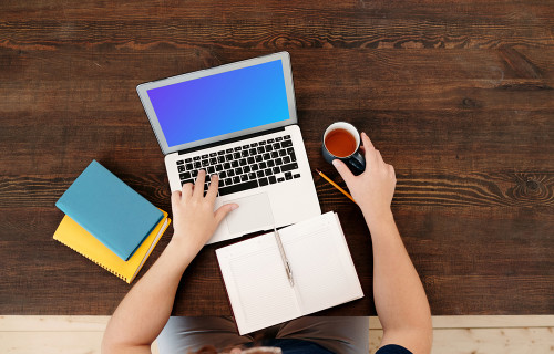 Man holding a coffee and using MacBook Air mockup