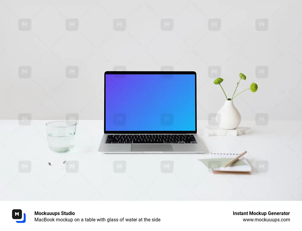 MacBook mockup on a table with glass of water at the side