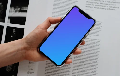 iPhone 12 Pro mockup held by user over an open magazine