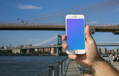 Sosteniendo el iPhone 6 mockup frente al puente de Brooklyn