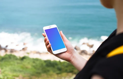 Sosteniendo el iPhone 7 mockup junto al océano