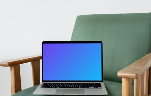 MacBook mockup en una silla verde con reposabrazos de madera