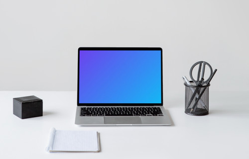 MacBook mockup sobre una mesa blanca con un cuaderno delante
