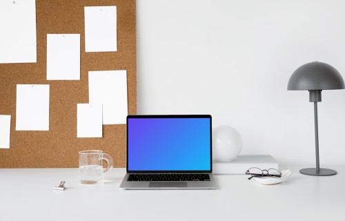MacBook mockup en una mesa de trabajo blanca con tablero de tareas a un lado