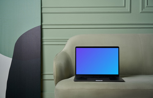MacBook mockup en un sofá con un cuadro al lado