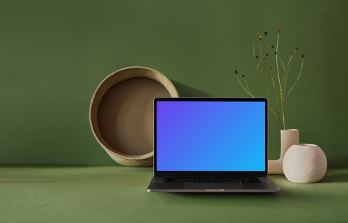 MacBook mockup sobre una losa verde con un jarrón de flores al lado