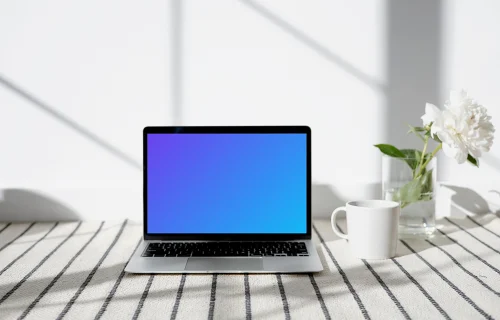 MacBook mockup sobre una alfombra estampada con una taza al lado