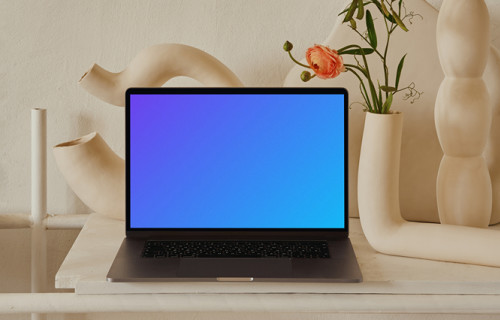 MacBook mockup en una mesa de color melocotón con un elegante jarrón de flores