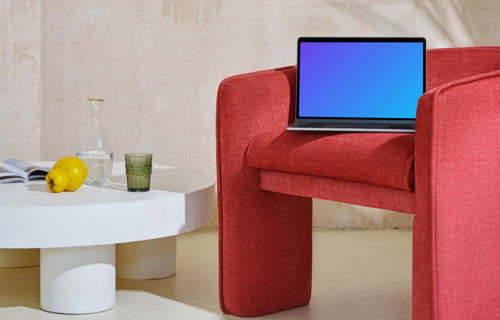 MacBook mockup en un sofá rojo con una mesa central cerca