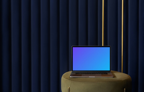 MacBook mockup en un taburete con una cortina azul de fondo