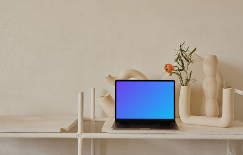 MacBook mockup sobre una mesa con un jarrón de flores de color melocotón al lado