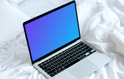 MacBook mockup en una cama blanca con café en un platillo
