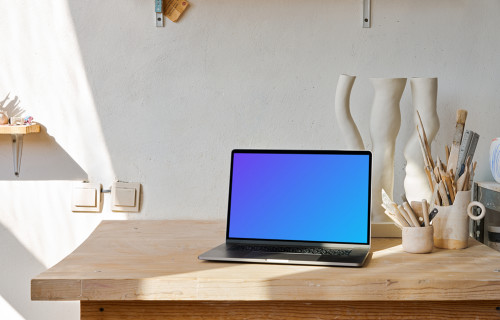 MacBook mockup en una mesa de madera con artesanía de madera al lado