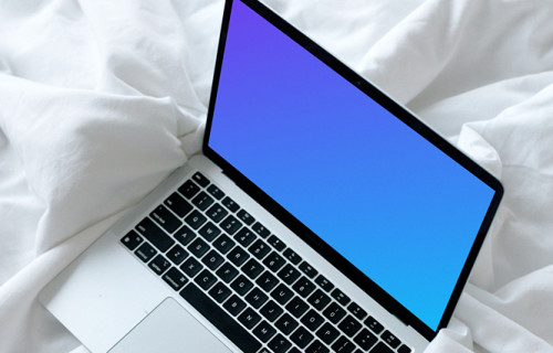 MacBook mockup descansando en una cama blanca