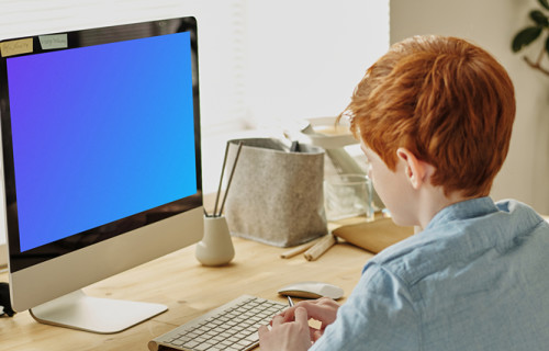 Mockup de un niño pelirrojo estudiando en un iMac
