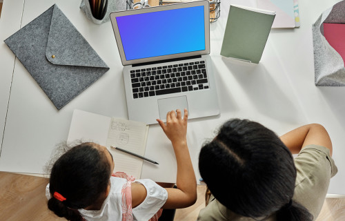 Un adulto enseñando algo a una niña en un MacBook Air mockup