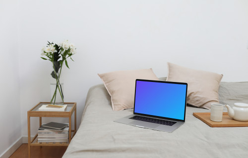 MacBook mockup en una cama con un juego de té al lado