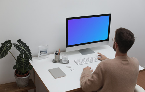 Usuario utilizando un iMac en su estación de trabajo
